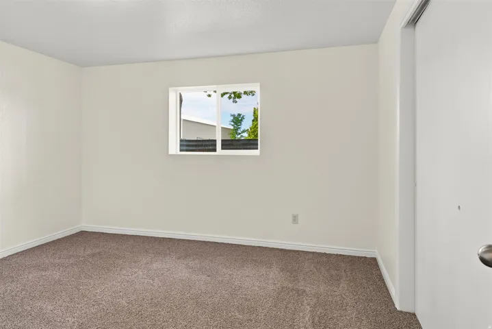 Room featuring light beige wall paint, brown carpeting, and white trim