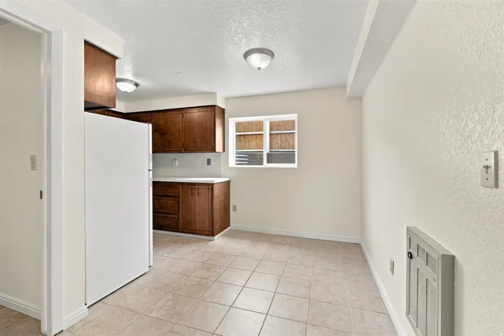 Kitchen area featuring wood-finish cabinetry, light countertops, and a tile floor