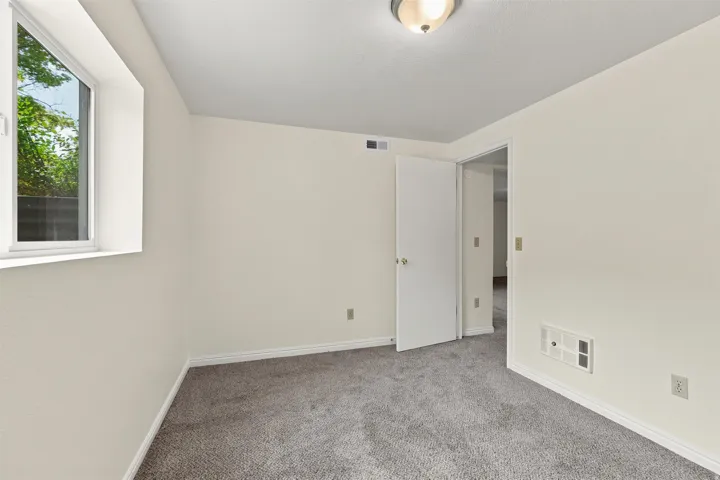 Neutral-toned room featuring a white window frame, painted walls, and gray carpet flooring