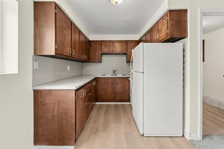 Compact kitchen featuring extensive wood-finish cabinetry, light-toned countertops, and wood-finish flooring