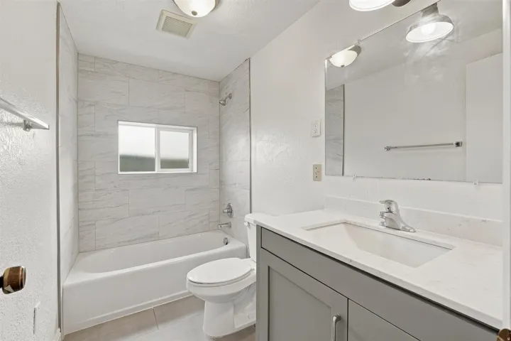 Bathroom featuring a white bathtub, tiled shower surround, and a window
