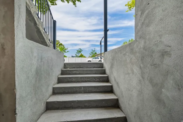 Concrete staircase featuring textured stucco walls and black metal railings