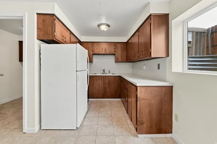 Efficient kitchen layout featuring abundant wood-finish cabinetry, light-toned countertops, and a white refrigerator