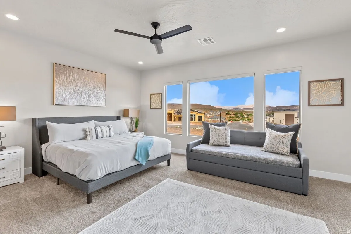 Spacious room with large windows offering a distant landscape, featuring a modern ceiling fan, recessed lighting, and carpeted flooring