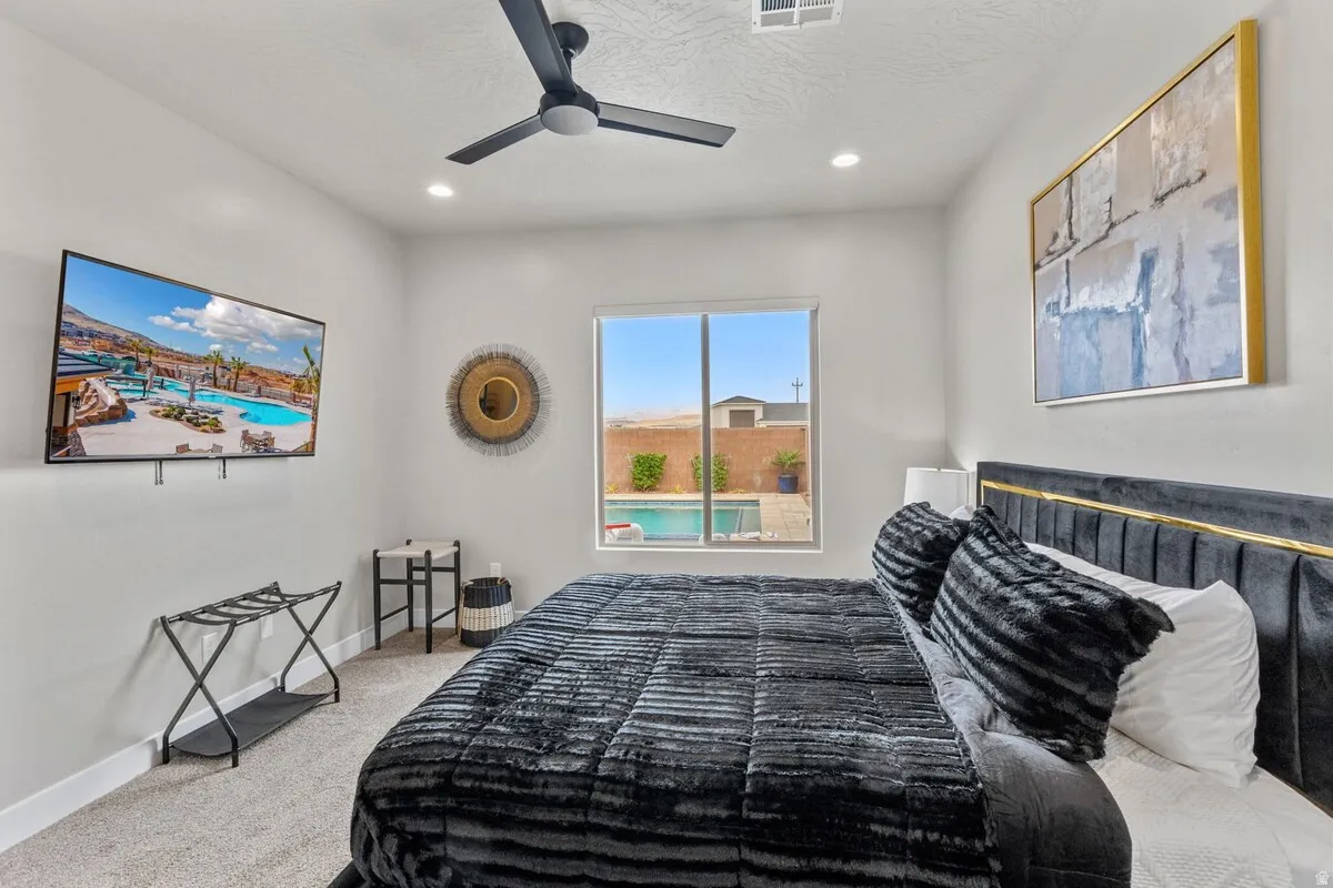 Bedroom featuring a ceiling fan with integrated lighting, recessed lighting, and a window offering a direct perspective of the outdoor pool