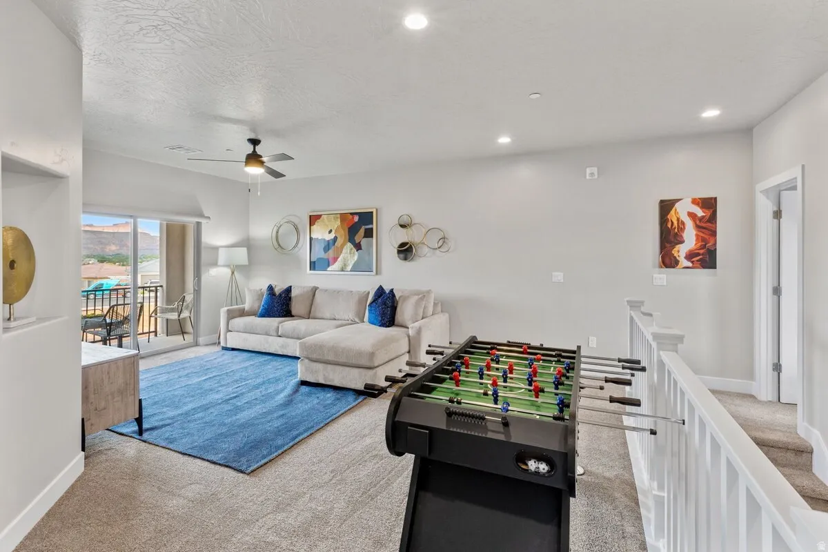 Spacious upper-level room featuring a sliding glass door to an outdoor balcony, recessed lighting, and a ceiling fan