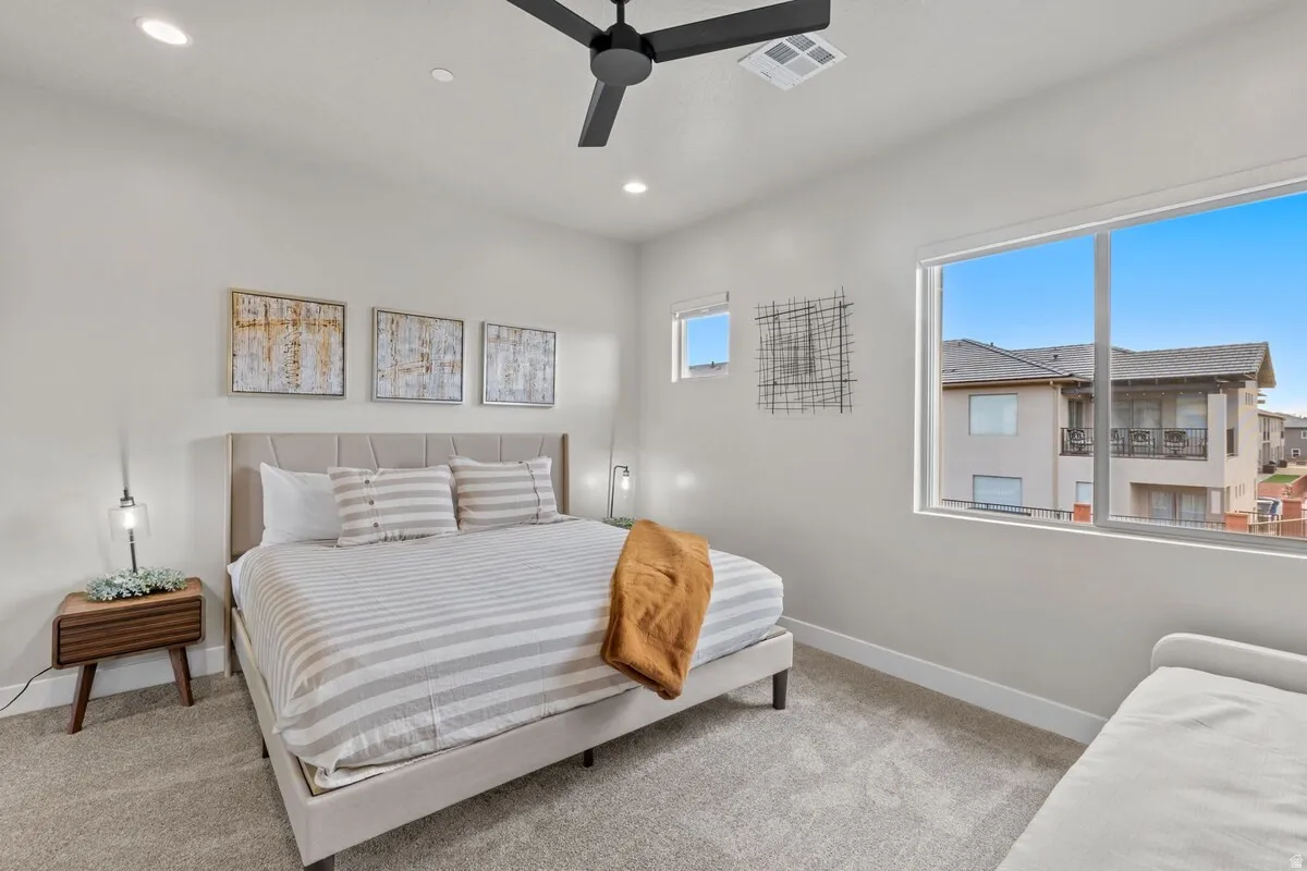 Bright bedroom featuring a large window, recessed lighting, and a ceiling fan