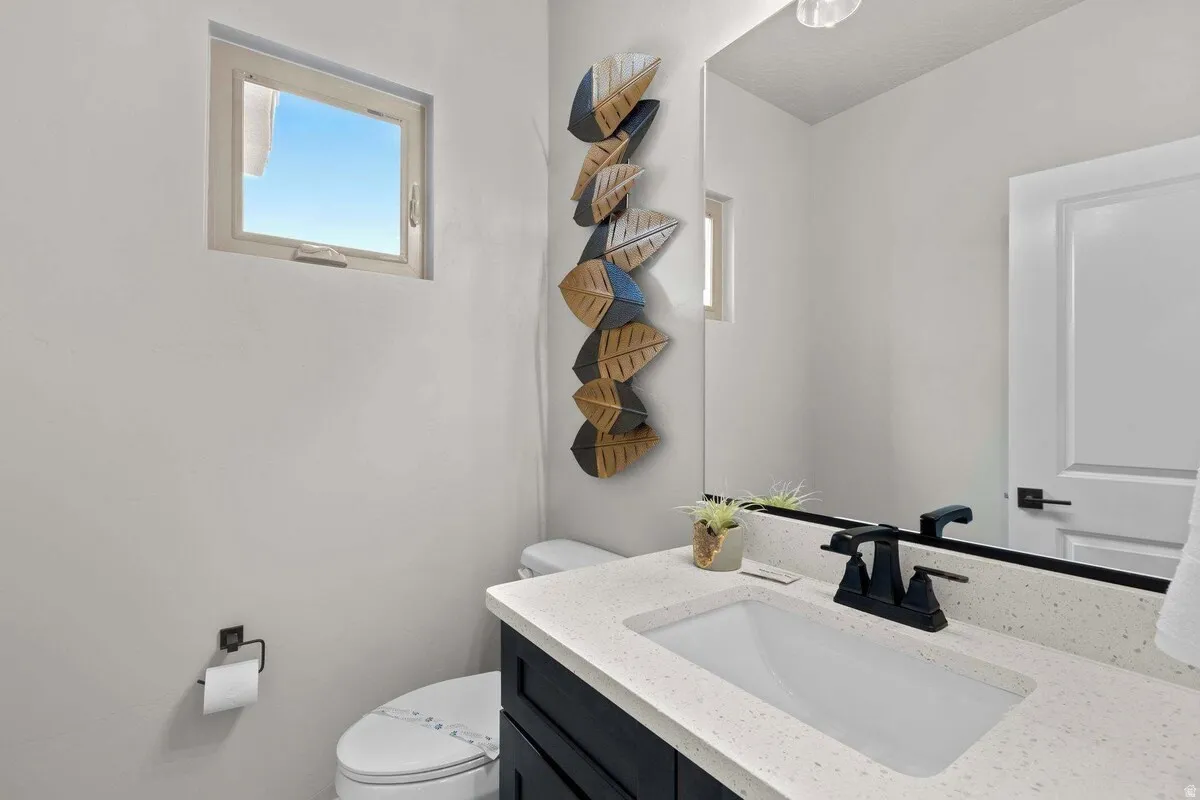 Bathroom featuring a vanity with a light speckled countertop, matte black faucet, and under-mount sink
