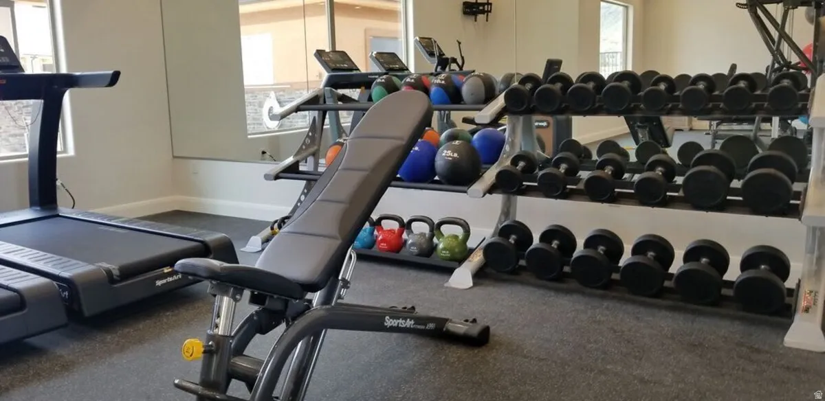 Dedicated fitness space featuring rubberized flooring, mirrored walls, and multiple windows