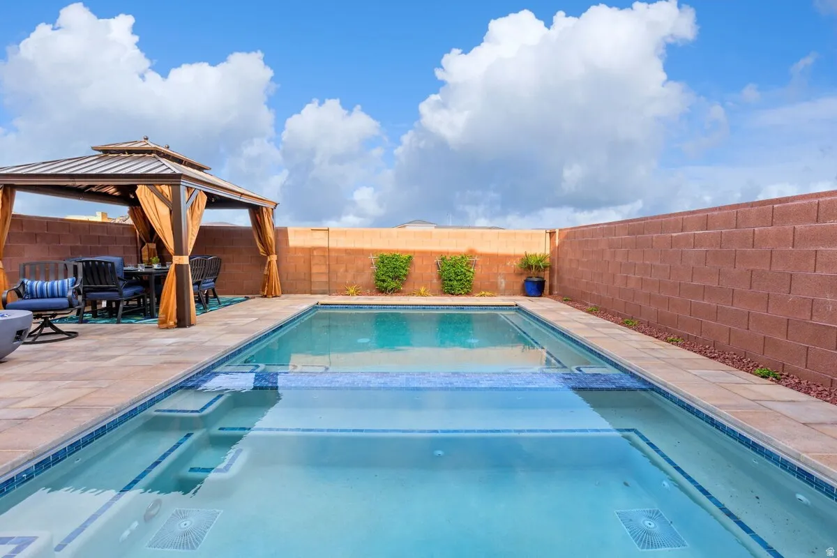 Outdoor living space featuring a rectangular swimming pool with integrated steps, surrounded by stone paver decking
