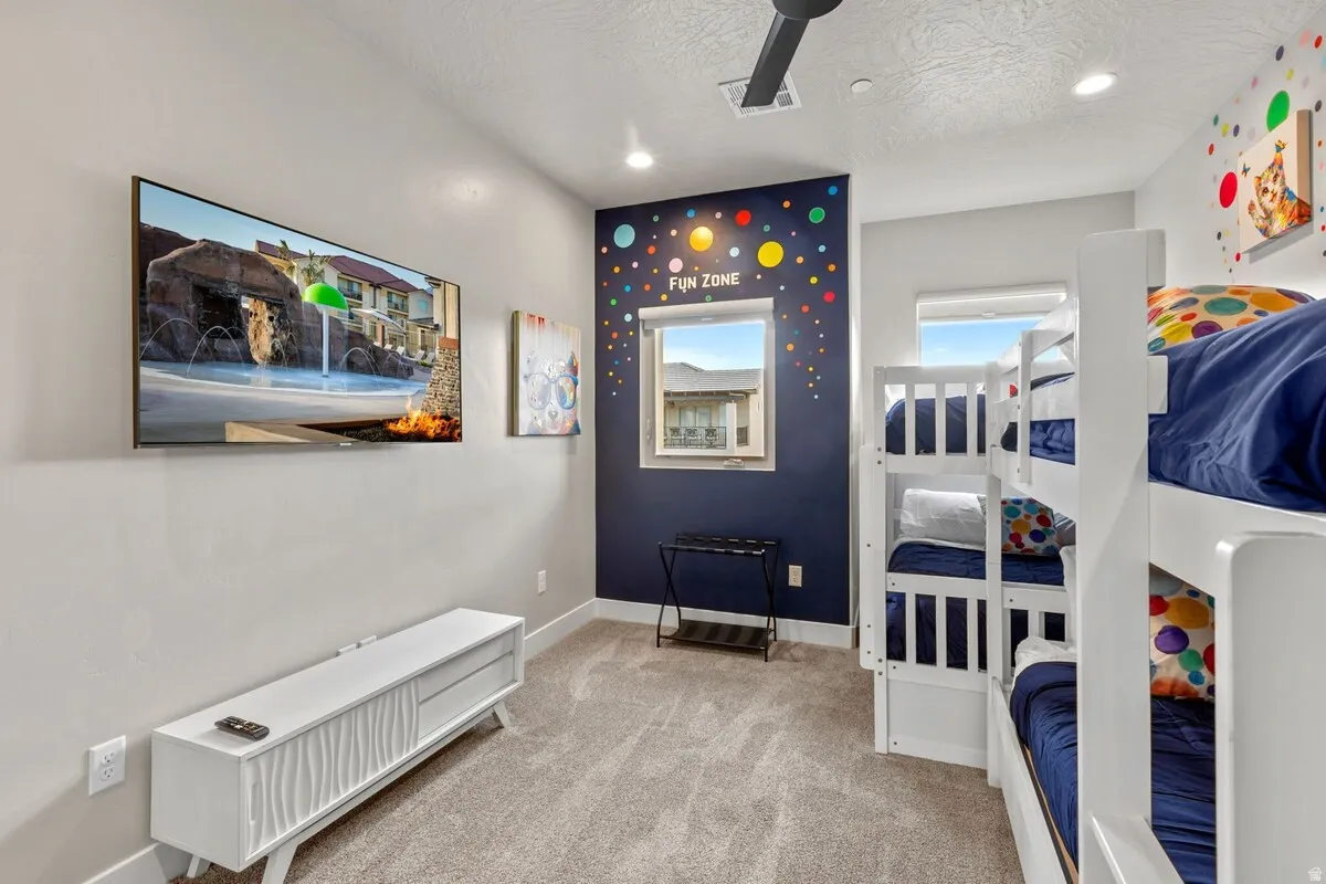 Carpeted interior space featuring a dark accent wall with decorative elements, two windows, and recessed lighting