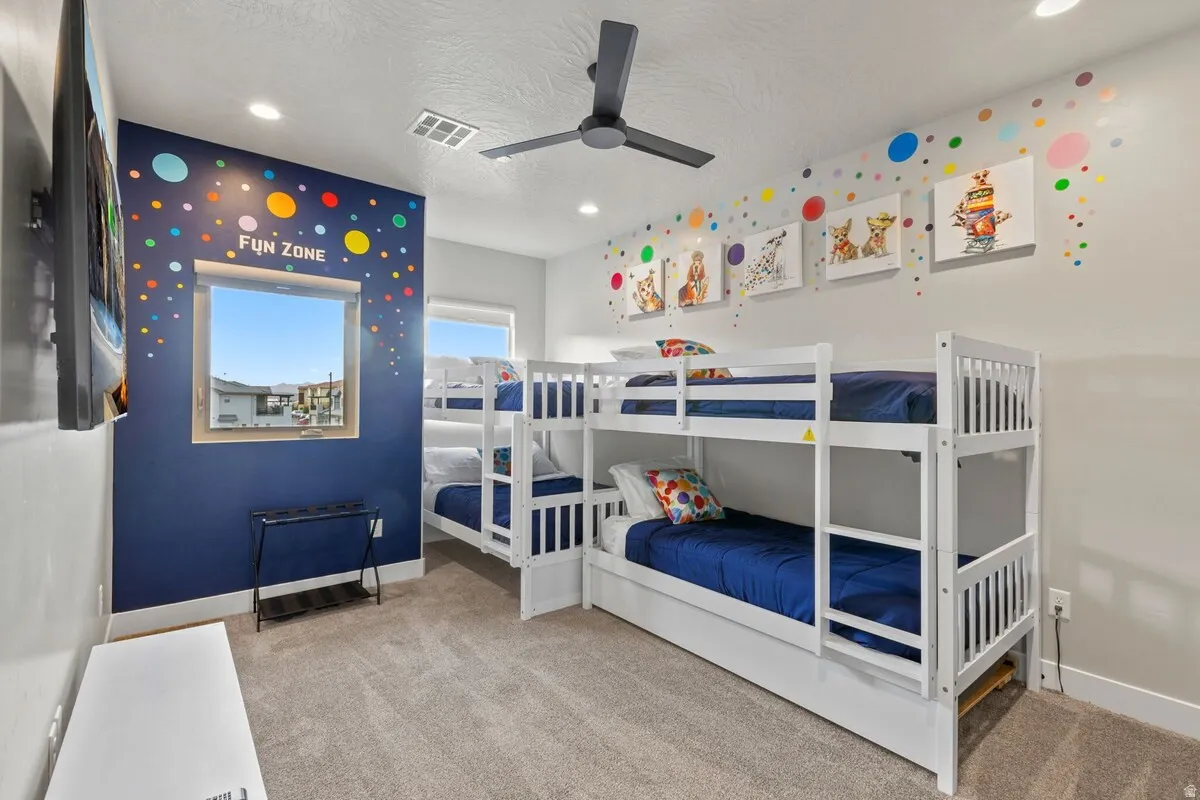 Spacious room featuring two white bunk beds, a dark blue accent wall, and recessed lighting