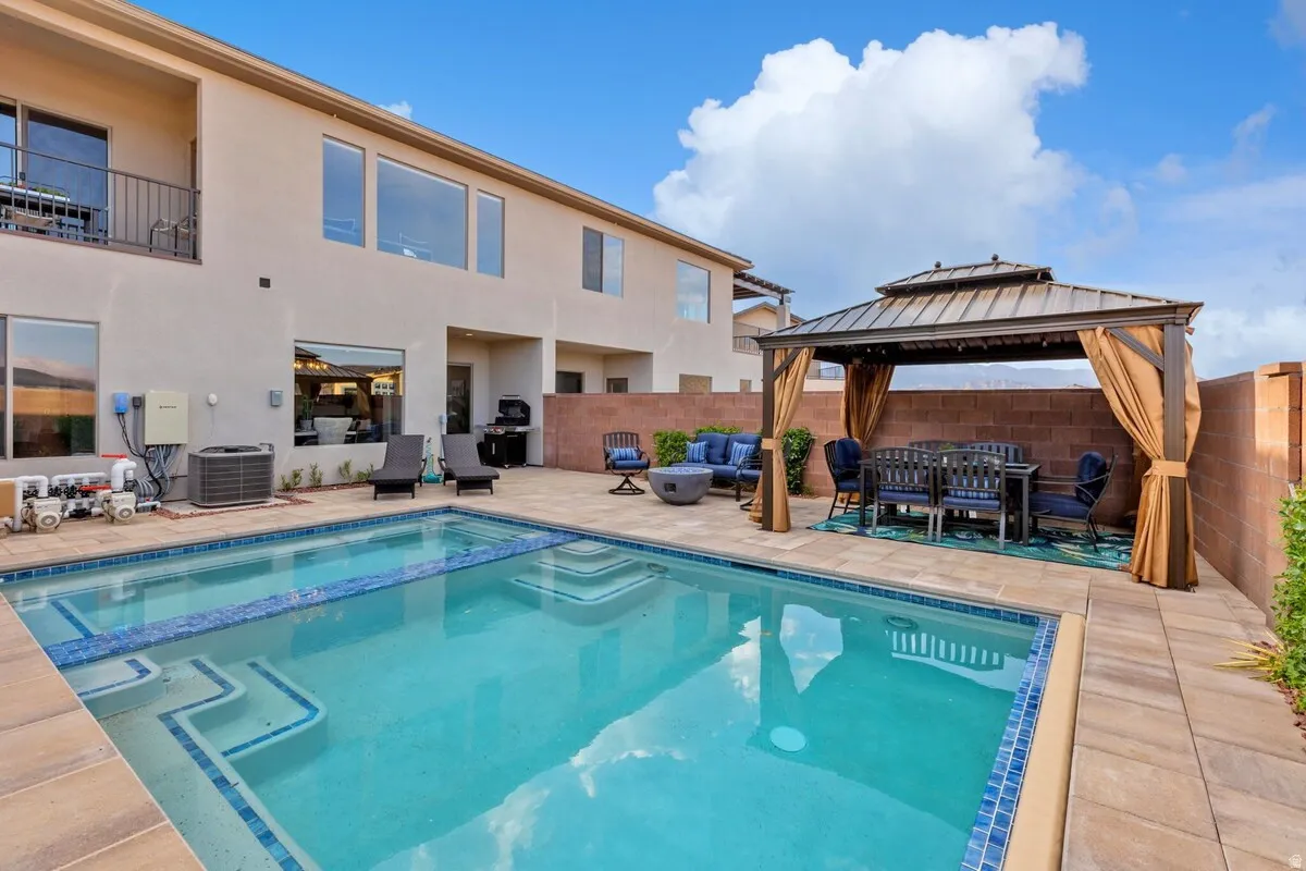 Rectangular swimming pool with integrated steps and blue tile accents, surrounded by paver decking