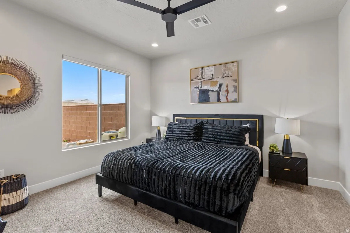 Spacious room featuring light gray walls, plush carpet flooring, a large window, a ceiling fan, and recessed lighting