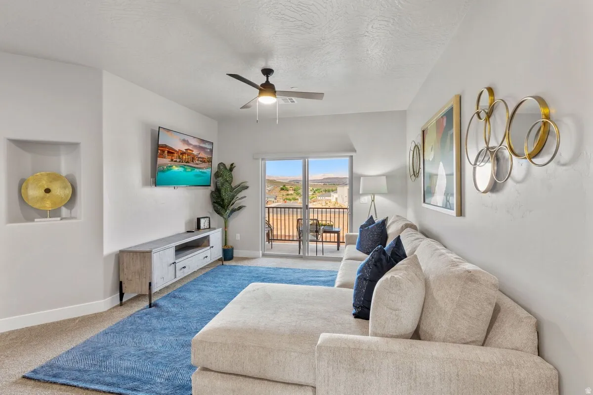 Living area featuring a ceiling fan, a built-in wall niche, and glass sliding doors opening to an exterior balcony with black metal railings