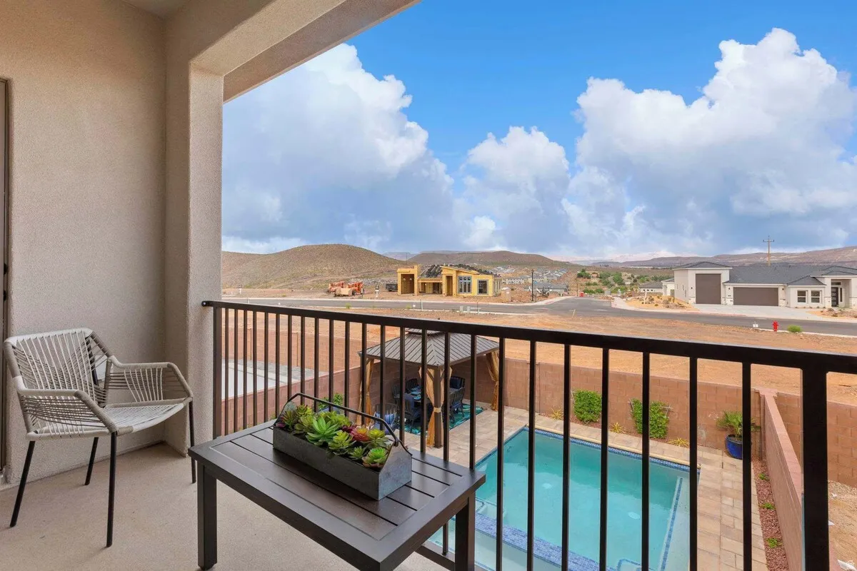 Private balcony with stucco finish, black metal railing, and desert mountain backdrop