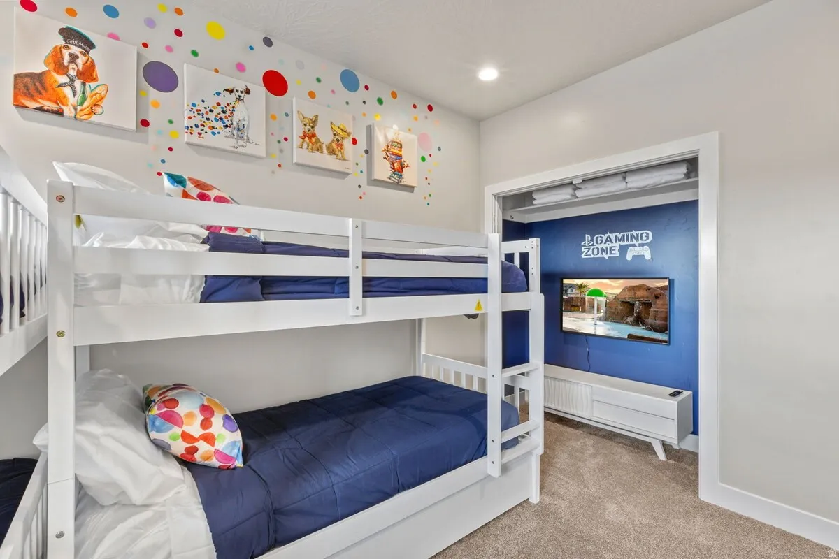 Carpeted room featuring bunk beds and a recessed entertainment area with built-in media console and wall-mounted television