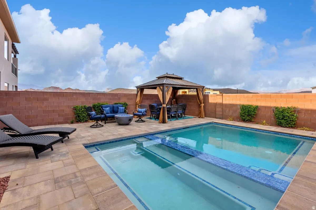 Outdoor living space featuring a rectangular pool with integrated steps, surrounded by paver decking