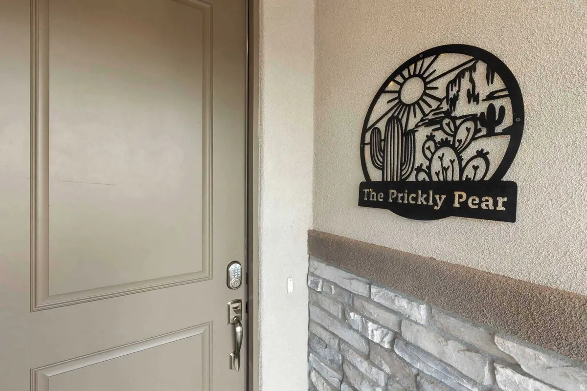 Entryway featuring a panel door with smart lock hardware, stone veneer wainscoting, and stucco exterior finish