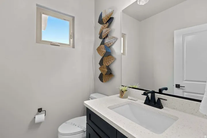 Bathroom featuring a vanity with a light speckled countertop, matte black faucet, and under-mount sink