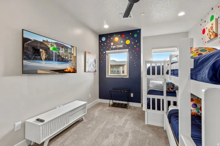 Carpeted interior space featuring a dark accent wall with decorative elements, two windows, and recessed lighting