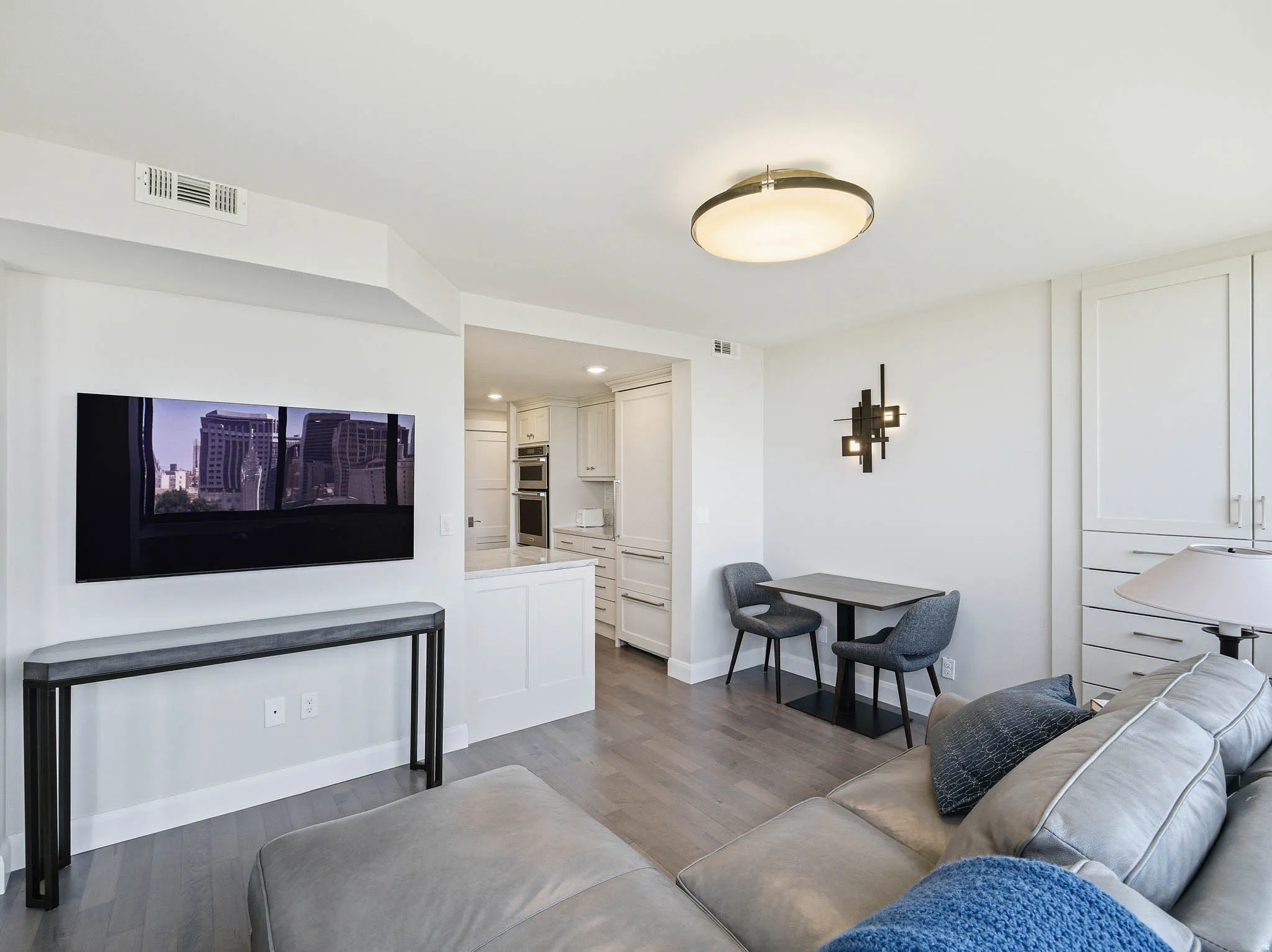 Open-concept living area with wood-finish flooring, recessed lighting, and a modern ceiling fixture