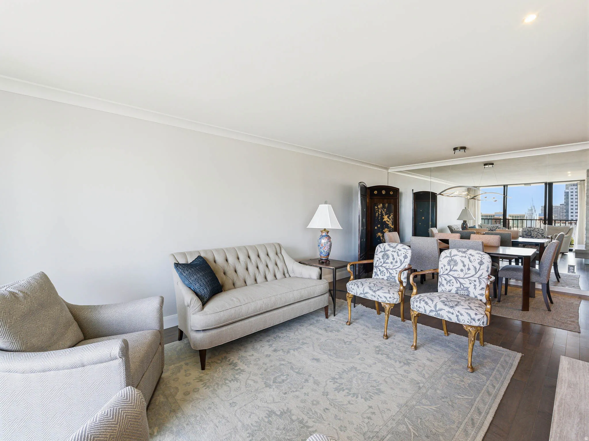 Spacious living area featuring light-colored walls, crown molding, and dark wood-finish flooring