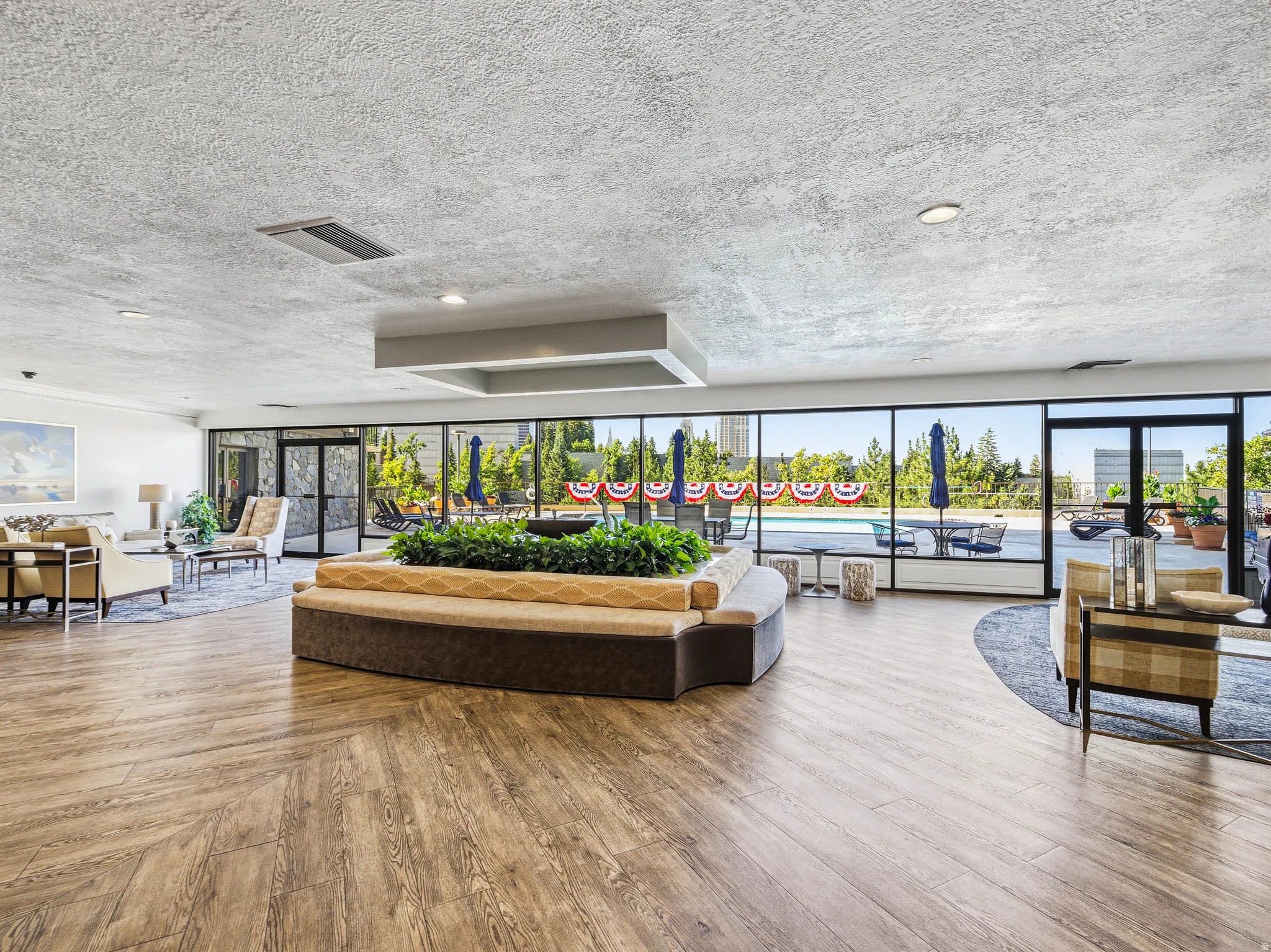 Spacious common area featuring wood-finish flooring, a large built-in planter with seating, and expansive floor-to-ceiling windows