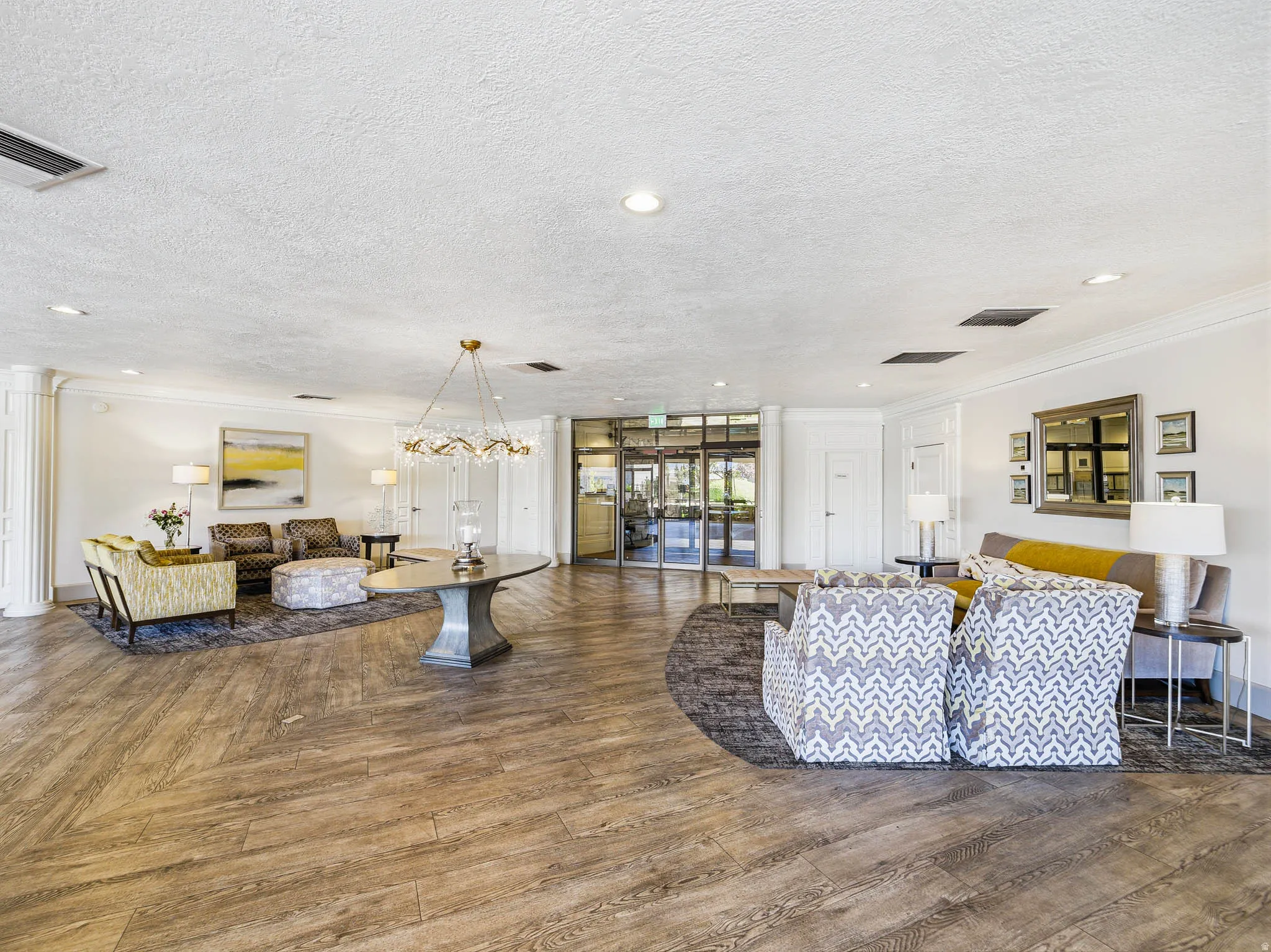 Spacious common area featuring wood-finish flooring, a contemporary chandelier, recessed lighting, and multiple seating arrangements