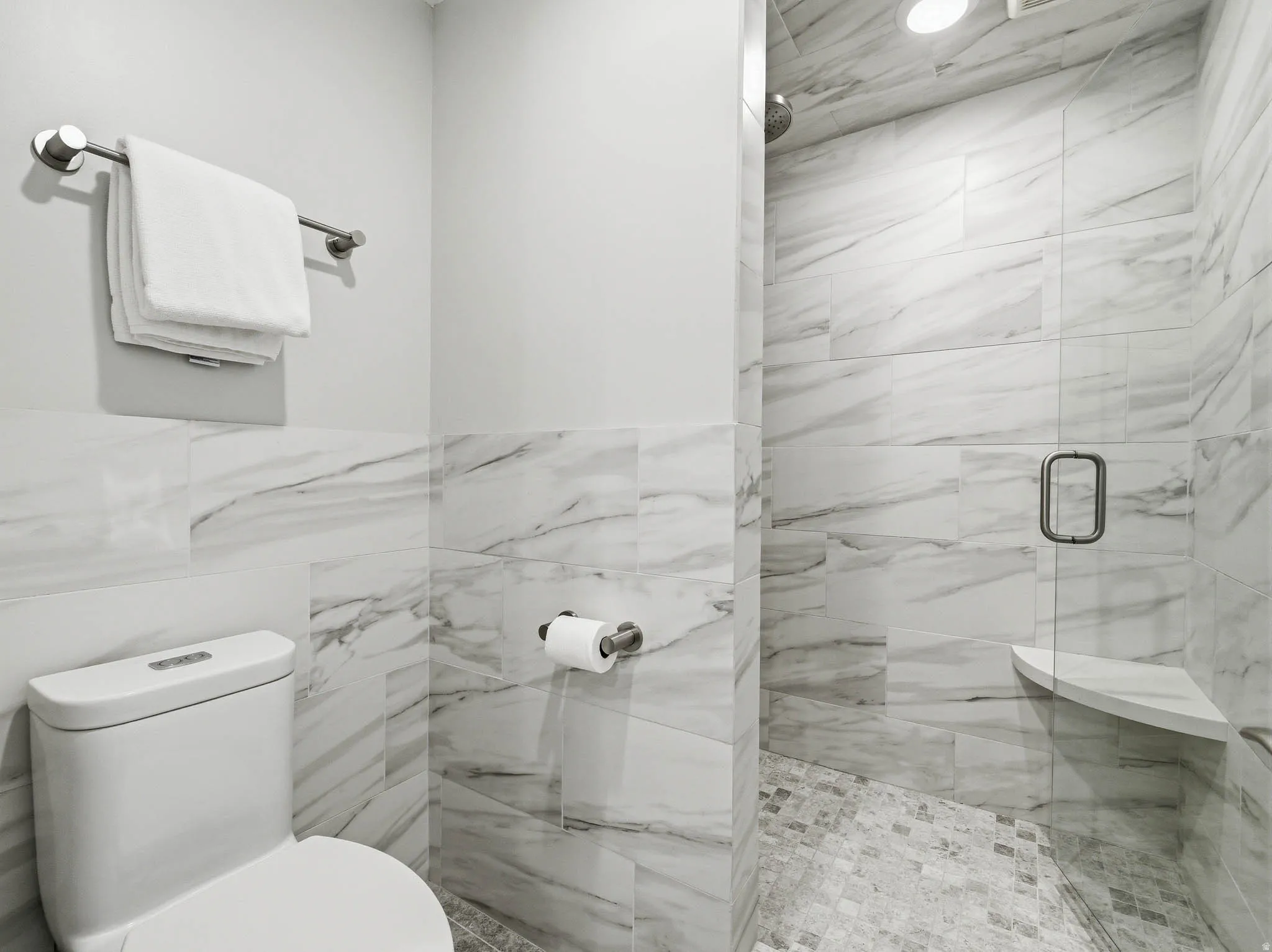 Walk-in shower with clear glass enclosure and corner shelf