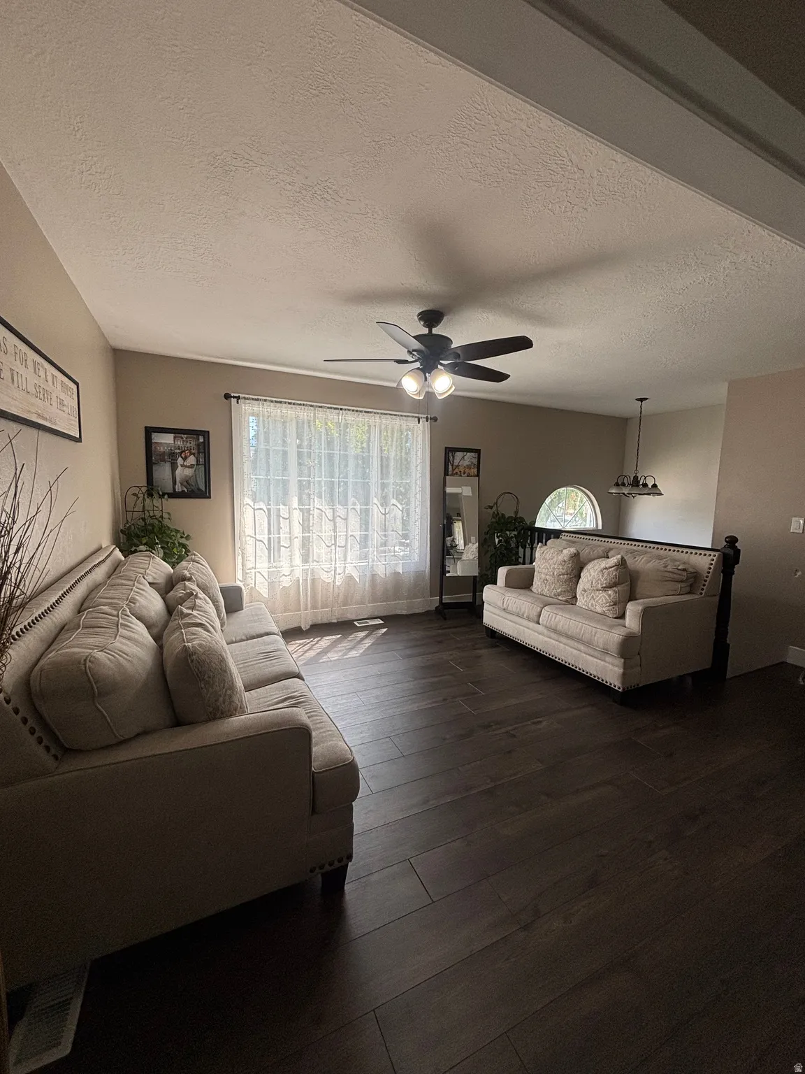 Spacious living area featuring wood-finish flooring, a vaulted ceiling, and a ceiling fan with integrated lighting