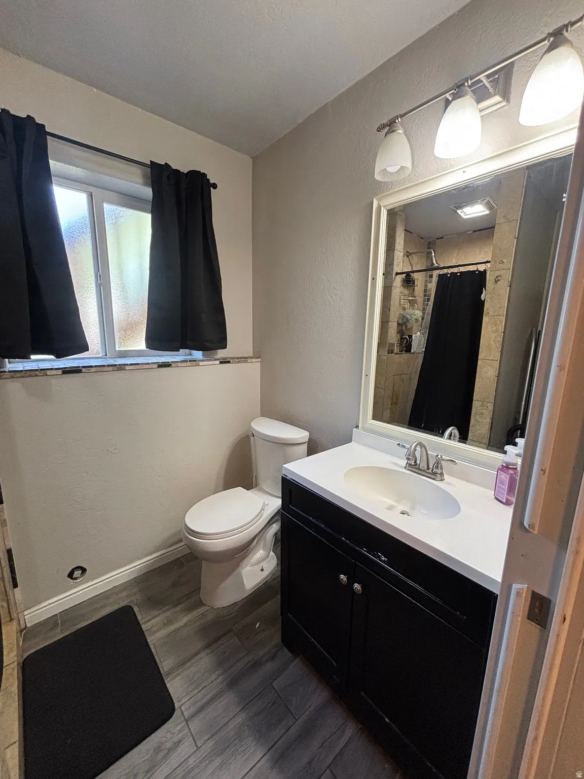 Bathroom featuring a dark wood-finish vanity with an integrated sink, a large wall mirror, and a three-light fixture
