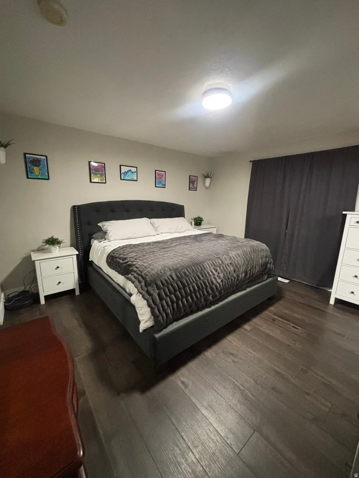 Spacious room featuring dark wood-finish flooring, light neutral-toned walls, and a ceiling-mounted light fixture