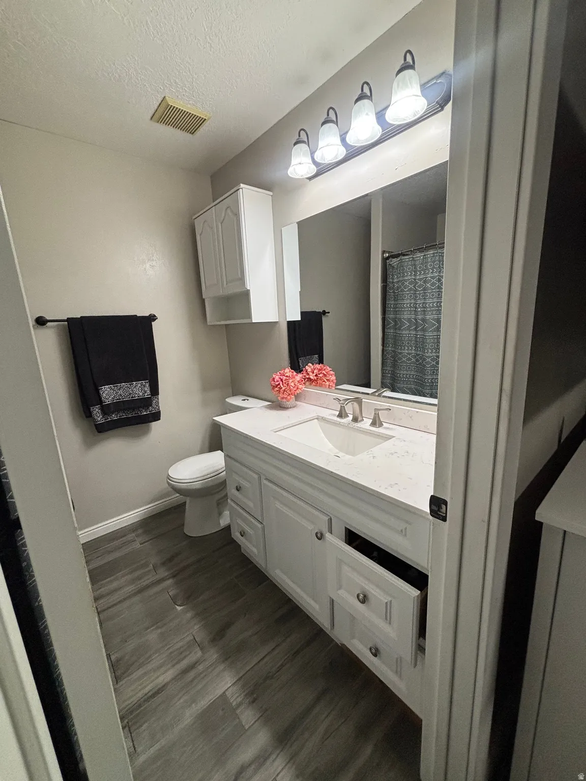 Modern bathroom featuring a single vanity with a white countertop and undermount sink, brushed nickel faucet, and coordinating hardware