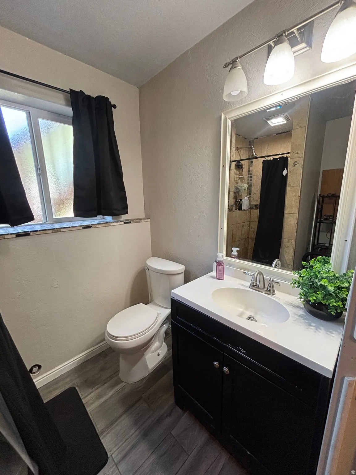 Bathroom featuring a dark wood-finish vanity with a white countertop and integrated sink, a large mirrored medicine cabinet, and a three-light fixture