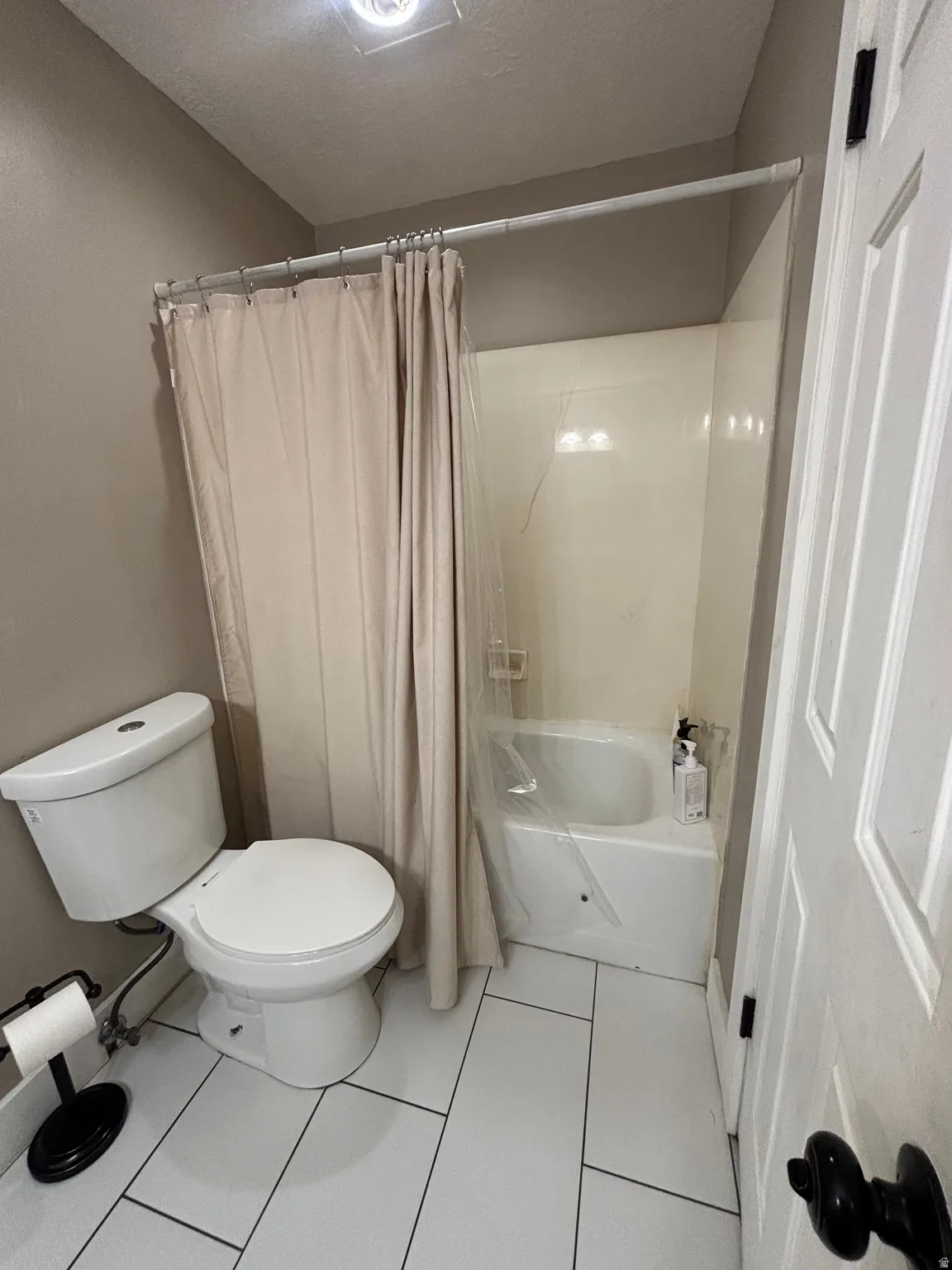 Bathroom with white rectangular tile flooring and a white toilet