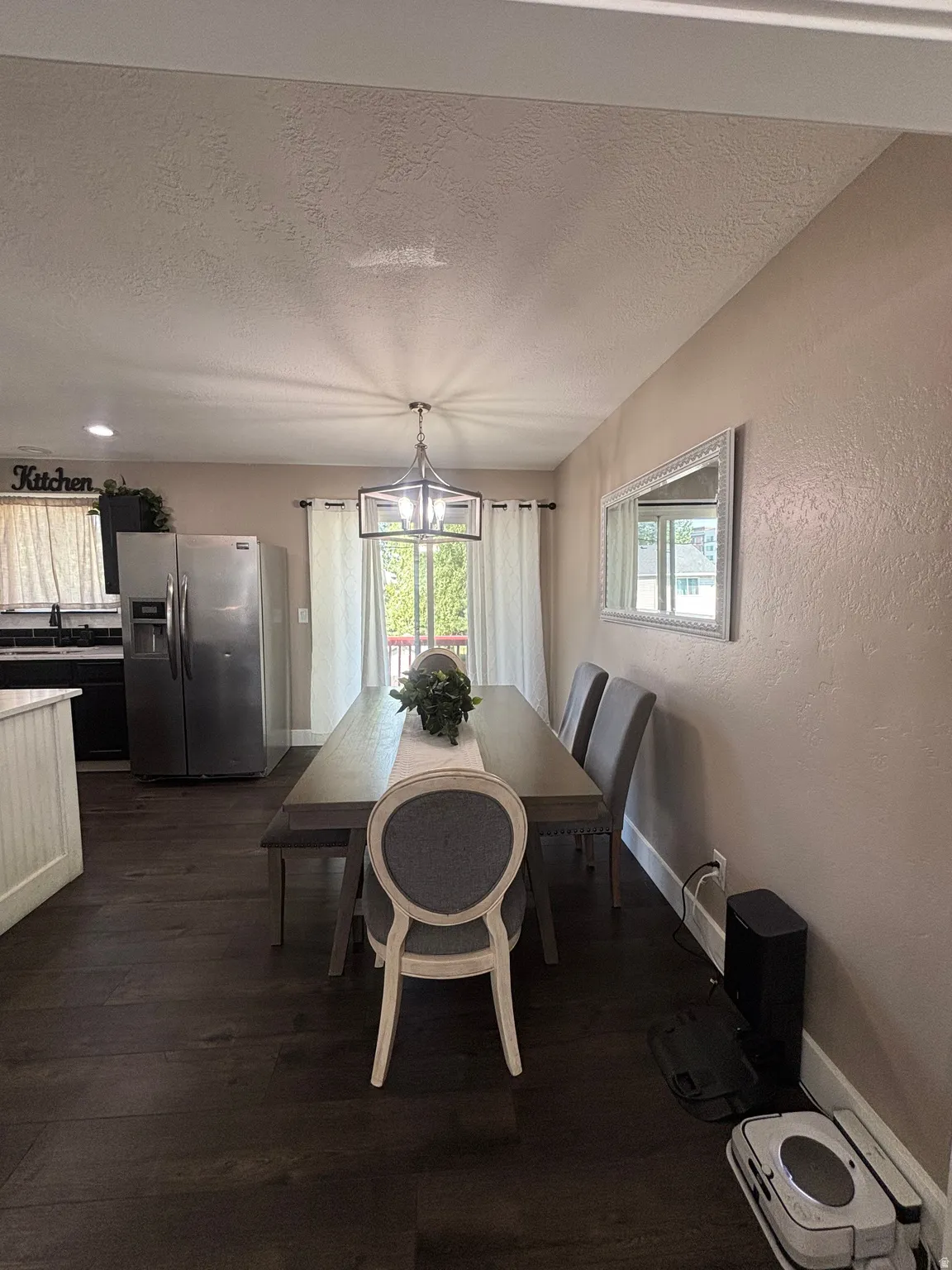 Open-concept dining area featuring dark wood-finish flooring, a contemporary chandelier, and direct access to an outdoor deck