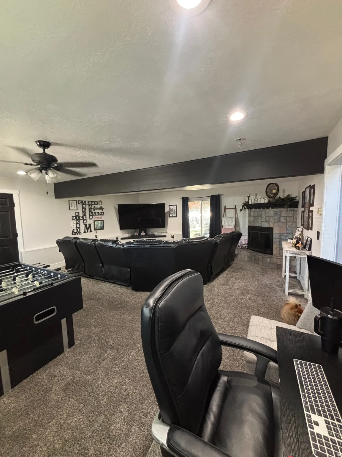 Spacious living area featuring neutral carpeting, recessed lighting, and a stone-clad fireplace