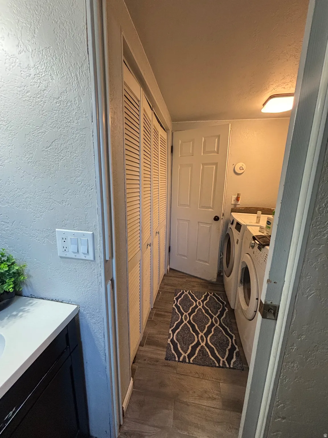 Laundry area with ceramic tile flooring, bi-fold louvered doors, and a flush-mount ceiling light fixture