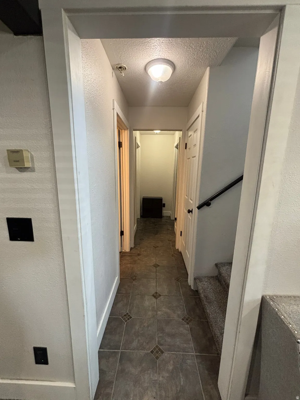 Hallway featuring tiled flooring, white trim work, and a ceiling-mounted light fixture