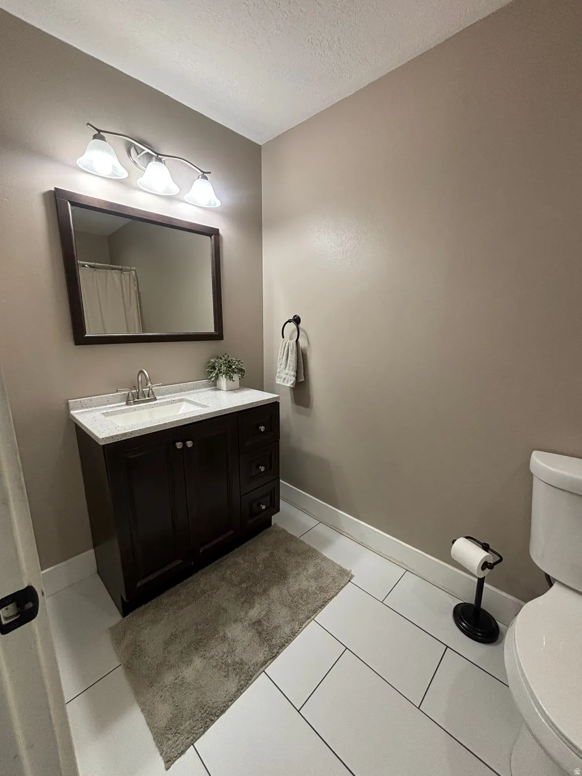 Vanity with espresso cabinetry, white countertop, and integrated sink