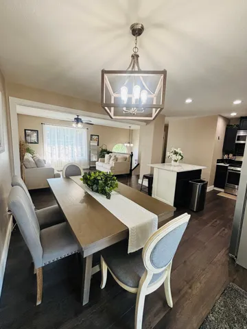 Open-concept dining area featuring wood-finish flooring, a contemporary chandelier, and a bright, airy aesthetic