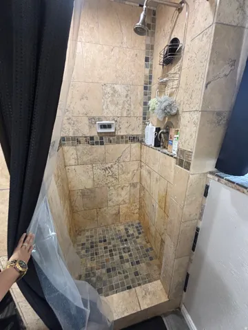 Tiled shower enclosure featuring a mosaic tile floor and full-height stone-look wall tiles