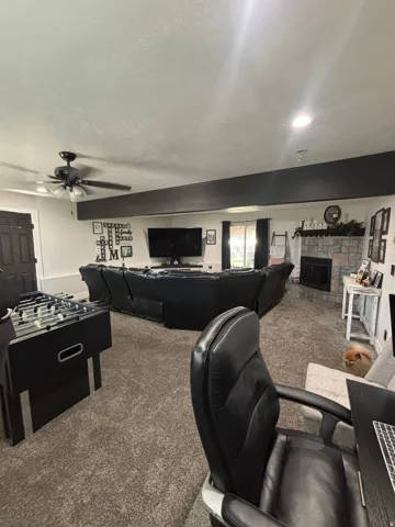 Spacious recreational room featuring recessed lighting, a ceiling fan, and a floor-to-ceiling stone fireplace