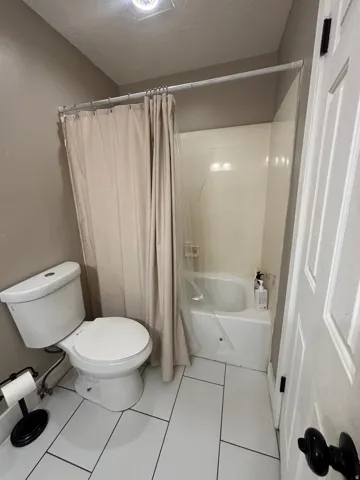 Bathroom with white rectangular tile flooring and a white toilet