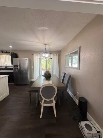 Open-concept dining area featuring dark wood-finish flooring, a contemporary chandelier, and direct access to an outdoor deck