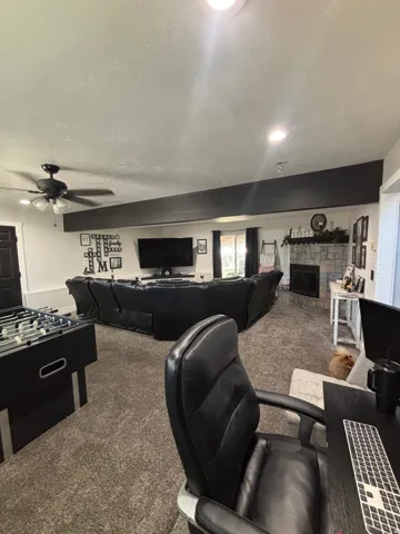Spacious living area featuring neutral carpeting, recessed lighting, and a stone-clad fireplace