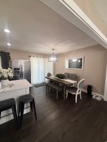 Open-concept living space featuring wood-finish flooring, recessed lighting, and a contemporary chandelier