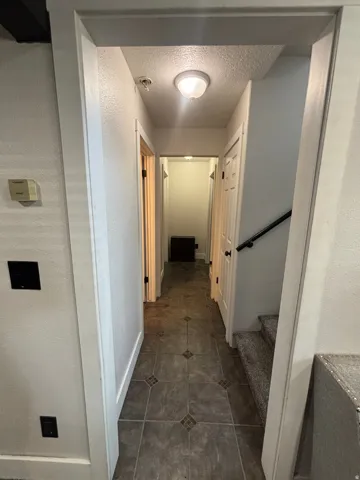 Hallway featuring tiled flooring, white trim work, and a ceiling-mounted light fixture