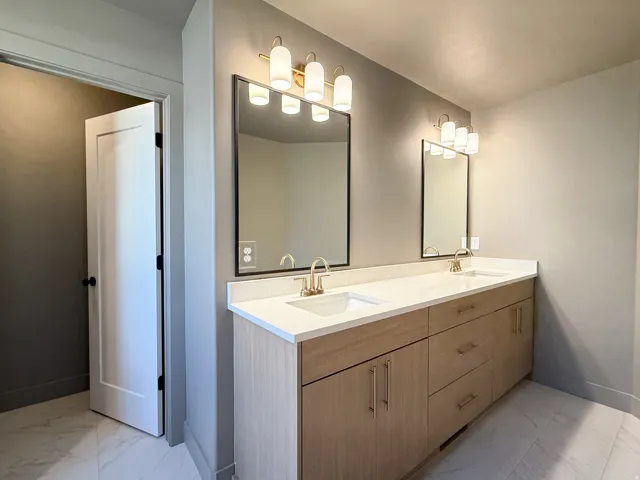 Dual vanity with light wood-finish cabinetry and gold-tone hardware